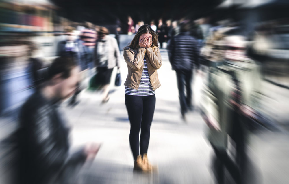 Panic attack in a public place thinking about an upcoming medical device audit. A depressed, sad person surrounded by people walking in a busy street.