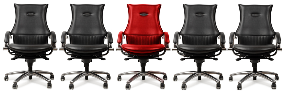 One red chair amongst black, concept of the hot seat, isolated on a white background. A red "hot seat" during an audit sitting among other black chairs. Image from Shutterstock.