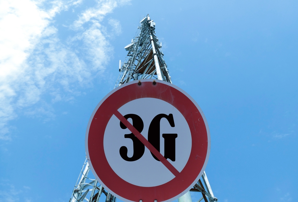 Illustration of the end of life for 3rd generation or 3G cell mobile networks. Road sign with 3G text against rural cellphone tower.